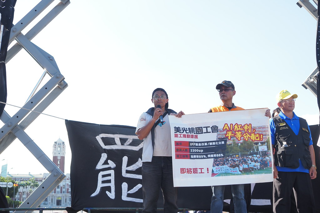 美光桃園工會在凱道舞台上發言，台上看板寫「即將罷工」